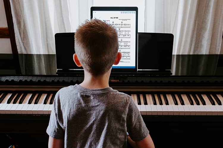 Young boy playing piano with Musicnotes app on iPad