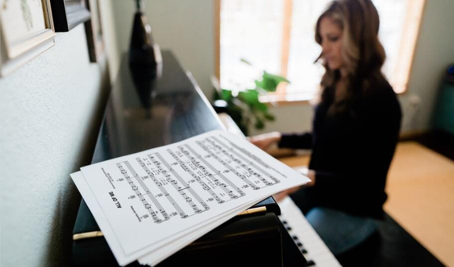 Printed sheet music on top of an upright piano that is being played